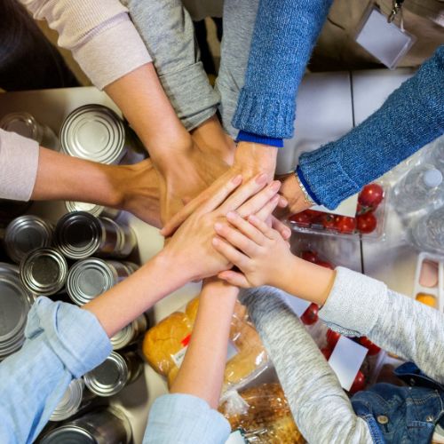 Meal preparation volunteers' hands joined together over food